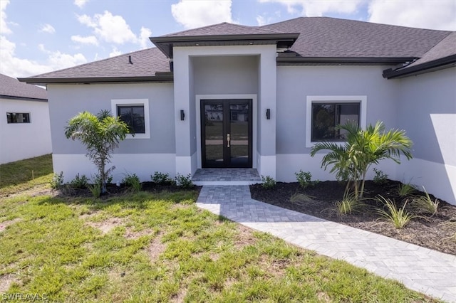 view of exterior entry with a lawn and french doors