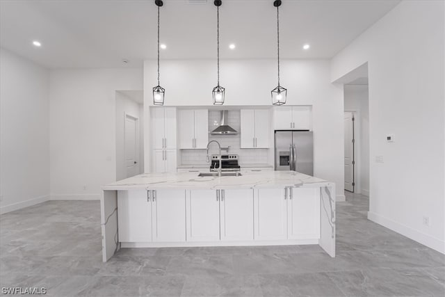 kitchen with pendant lighting, white cabinetry, stainless steel refrigerator with ice dispenser, and wall chimney range hood