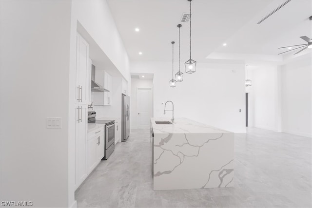 kitchen featuring decorative light fixtures, ceiling fan, appliances with stainless steel finishes, white cabinets, and a kitchen island with sink