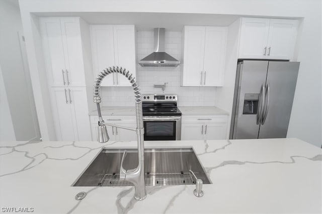 kitchen with white cabinets, appliances with stainless steel finishes, backsplash, and wall chimney exhaust hood