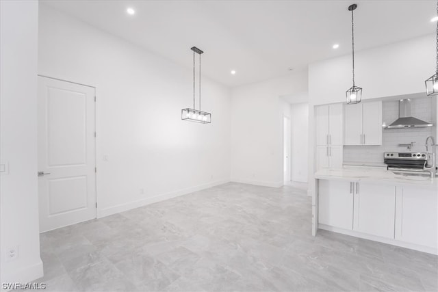 interior space featuring light tile floors, backsplash, wall chimney range hood, decorative light fixtures, and white cabinetry