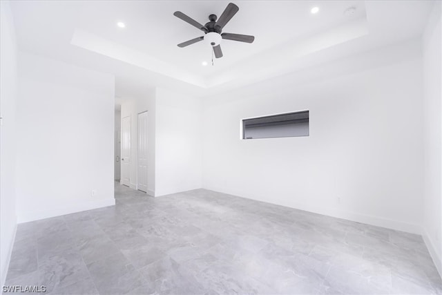 spare room with light tile floors, ceiling fan, and a tray ceiling