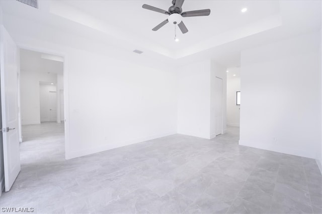 spare room with light tile floors, ceiling fan, and a raised ceiling