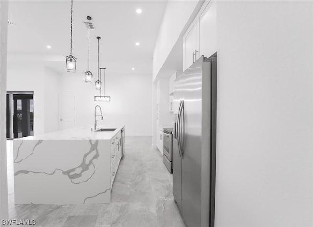 kitchen featuring a center island with sink, stainless steel appliances, decorative light fixtures, and white cabinetry