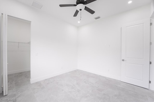 unfurnished bedroom featuring a spacious closet, a closet, ceiling fan, and light tile floors