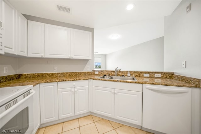 kitchen with white dishwasher, light tile floors, dark stone counters, white cabinetry, and sink