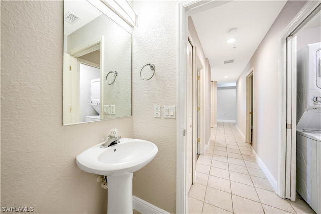 bathroom featuring tile flooring and stacked washer and dryer