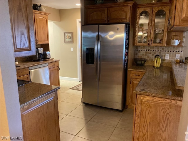 kitchen with light tile floors, dark stone counters, tasteful backsplash, and stainless steel appliances