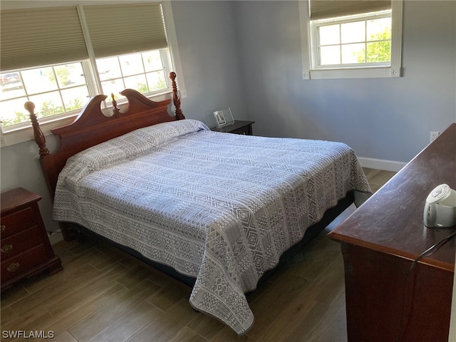 bedroom with multiple windows and dark wood-type flooring