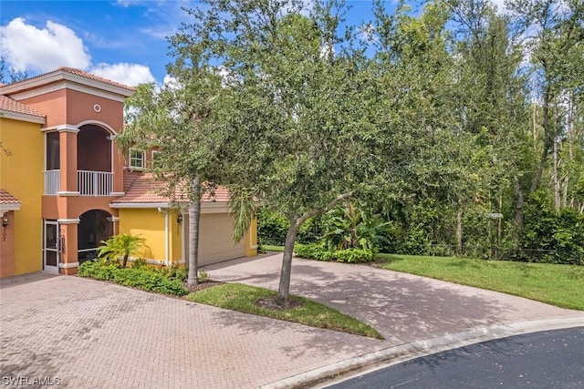 view of front of home featuring a balcony, a garage, and a front yard