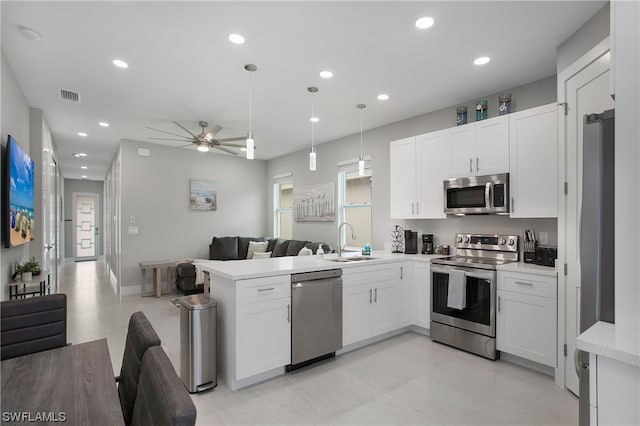 kitchen with pendant lighting, stainless steel appliances, ceiling fan, white cabinetry, and sink