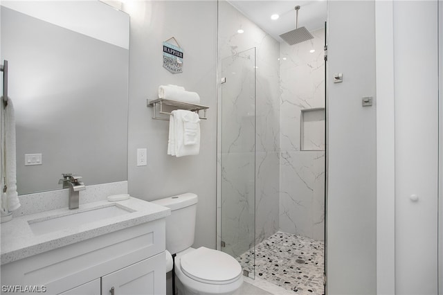 bathroom with a shower with shower door, vanity with extensive cabinet space, and toilet