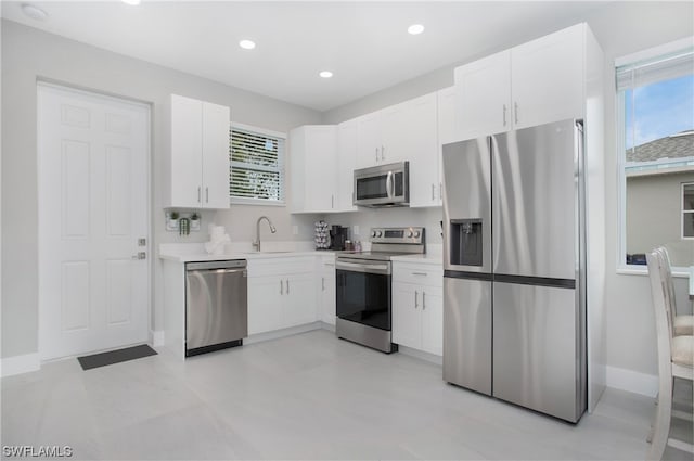 kitchen featuring sink, stainless steel appliances, white cabinetry, and a wealth of natural light