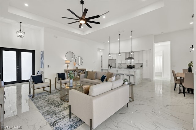 living room featuring french doors, ceiling fan, a tray ceiling, and light tile floors