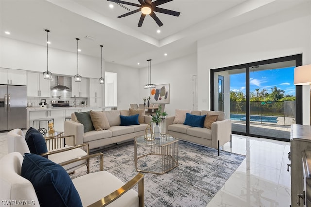 tiled living room with ceiling fan, a high ceiling, and a tray ceiling