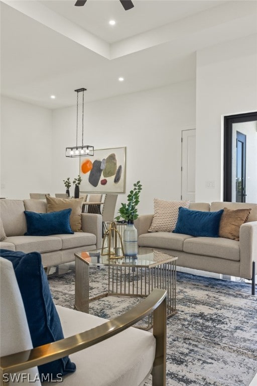 living room featuring ceiling fan and a tray ceiling