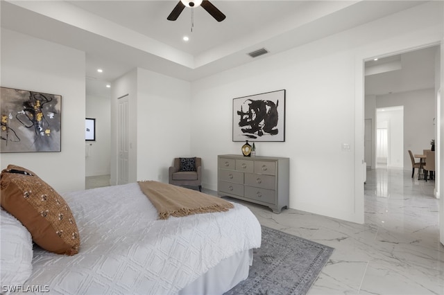 bedroom with a closet, ceiling fan, light tile floors, ensuite bathroom, and a tray ceiling