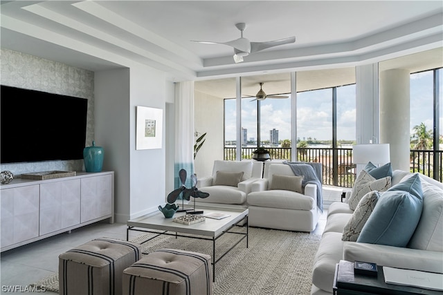 tiled living room with a raised ceiling and ceiling fan