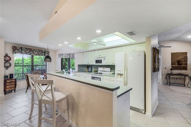 kitchen featuring white cabinets, light tile patterned floors, white appliances, and a kitchen breakfast bar