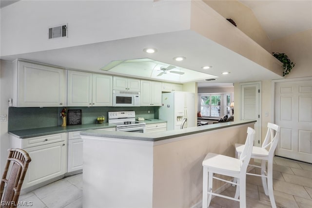 kitchen featuring white cabinetry, ceiling fan, white appliances, a breakfast bar area, and a kitchen island