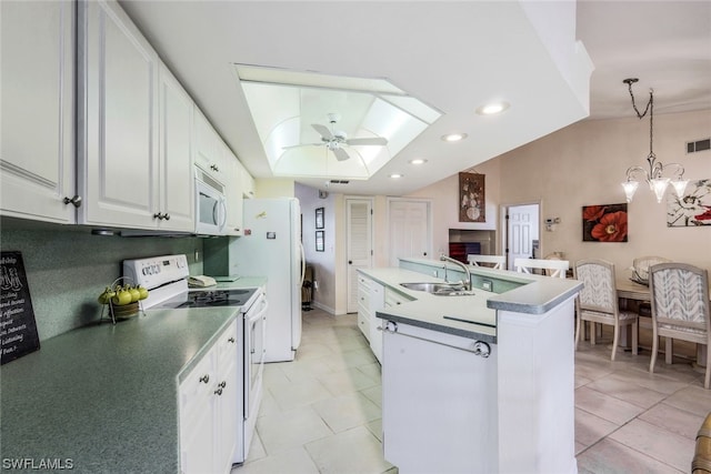 kitchen with white cabinetry, sink, lofted ceiling with skylight, white appliances, and ceiling fan with notable chandelier