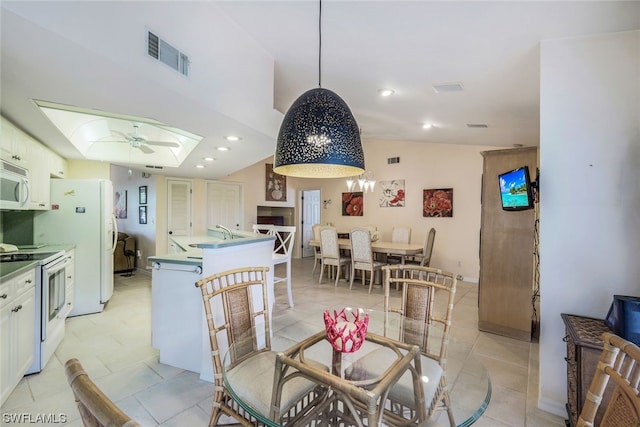 dining area with light tile patterned floors, sink, ceiling fan, and vaulted ceiling with skylight