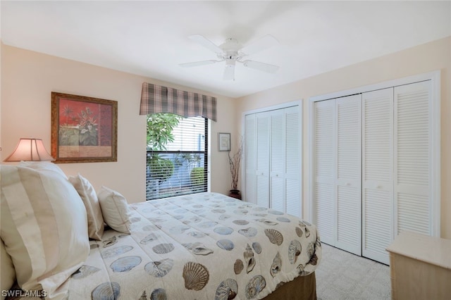 bedroom featuring light carpet, ceiling fan, and multiple closets