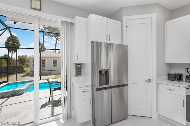 kitchen featuring stainless steel fridge and white cabinetry