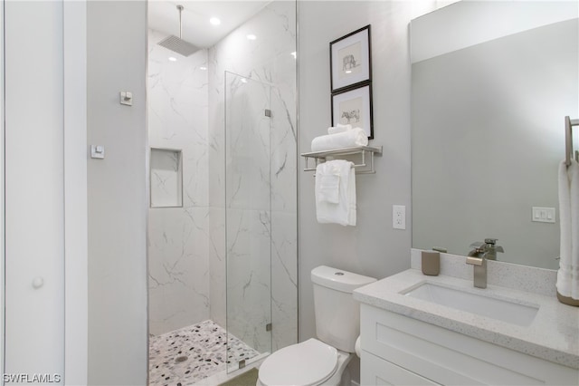 bathroom featuring toilet, tiled shower, and large vanity