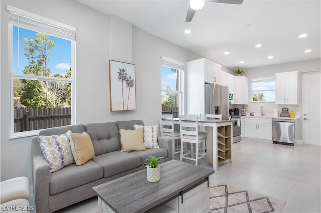 living room with light tile floors, sink, ceiling fan, and a healthy amount of sunlight