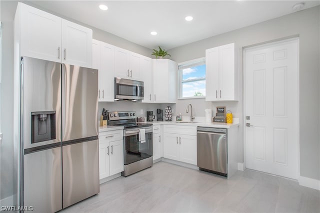 kitchen featuring light tile floors, appliances with stainless steel finishes, white cabinetry, and sink