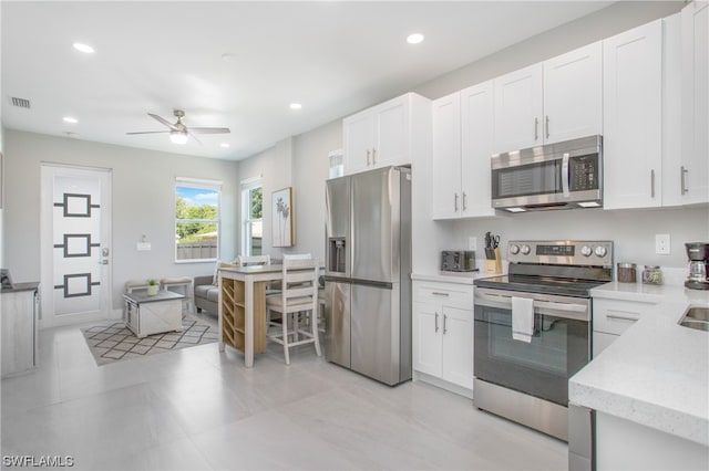 kitchen featuring white cabinets, ceiling fan, light tile flooring, and stainless steel appliances