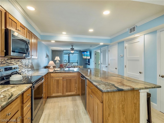 kitchen featuring ceiling fan, appliances with stainless steel finishes, sink, light wood-type flooring, and tasteful backsplash