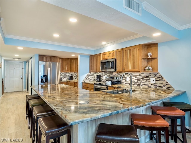 kitchen with a kitchen breakfast bar, tasteful backsplash, appliances with stainless steel finishes, light stone counters, and sink