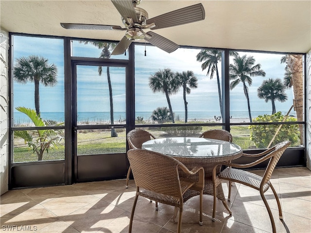 sunroom / solarium with ceiling fan and a water view