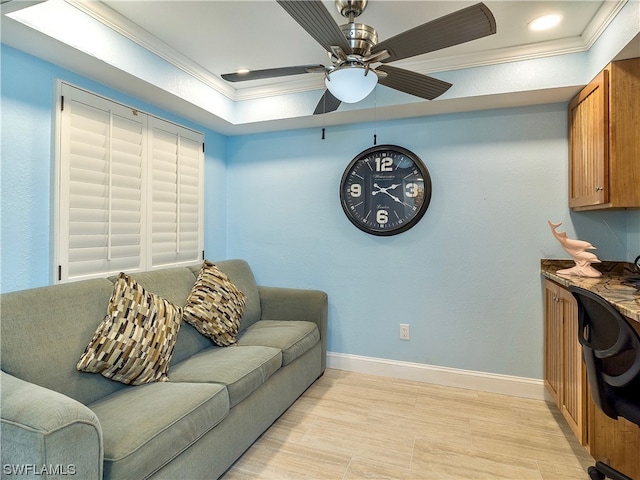 living room featuring light hardwood / wood-style flooring, a tray ceiling, ornamental molding, and ceiling fan