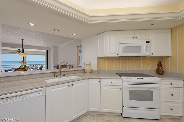 kitchen featuring ornamental molding, white appliances, white cabinets, a water view, and sink