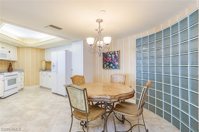 dining room with an inviting chandelier, a raised ceiling, and light tile floors