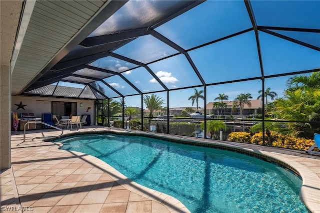 view of swimming pool featuring glass enclosure, a patio area, and a water view