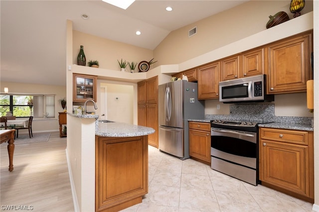 kitchen featuring light stone countertops, stainless steel appliances, sink, high vaulted ceiling, and light hardwood / wood-style floors