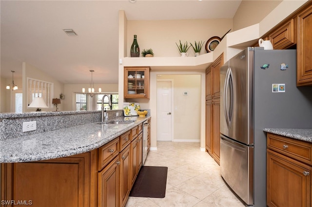 kitchen featuring light stone countertops, appliances with stainless steel finishes, sink, pendant lighting, and a notable chandelier