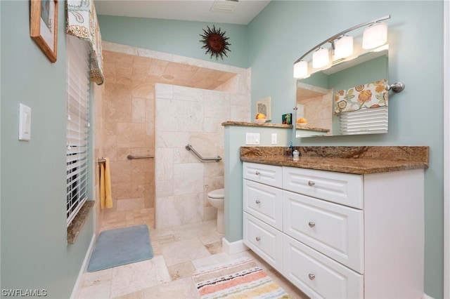 bathroom featuring vanity, toilet, and tiled shower