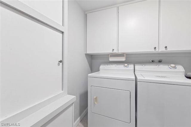 clothes washing area with cabinets and independent washer and dryer