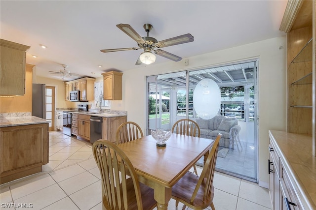 dining space featuring ceiling fan, sink, and light tile patterned flooring