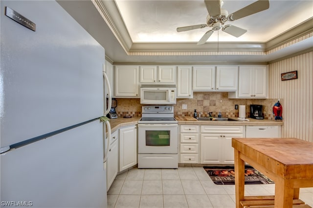 kitchen featuring ceiling fan, white appliances, white cabinets, a raised ceiling, and tasteful backsplash