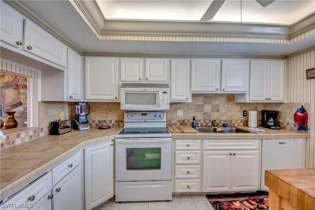 kitchen with white appliances, white cabinets, tasteful backsplash, and sink