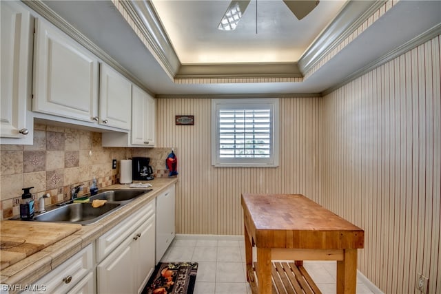 kitchen with ceiling fan, tasteful backsplash, white cabinets, a raised ceiling, and sink