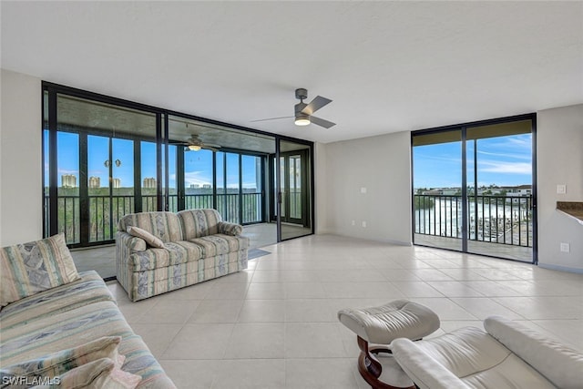 living room featuring ceiling fan, expansive windows, a water view, and plenty of natural light