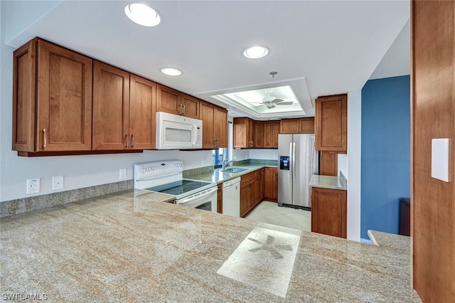 kitchen featuring ceiling fan, sink, kitchen peninsula, white appliances, and a tray ceiling