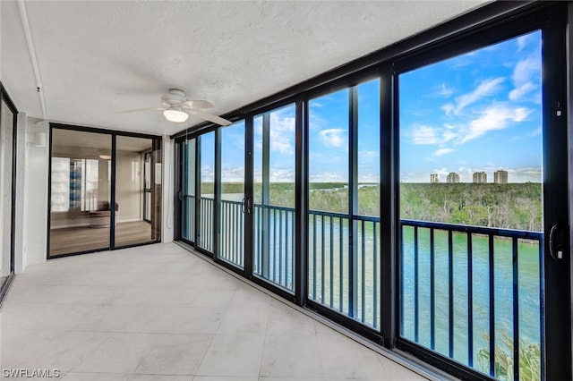 unfurnished sunroom featuring ceiling fan and a healthy amount of sunlight